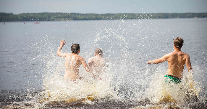 Personer som springer ut i en sjö så att vattnet stänker.