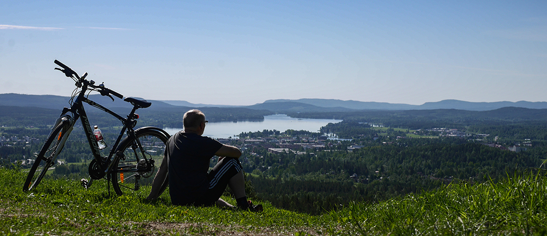 Person sittandes vid sin cykel på ett berg med utsikt över staden Bollnäs.