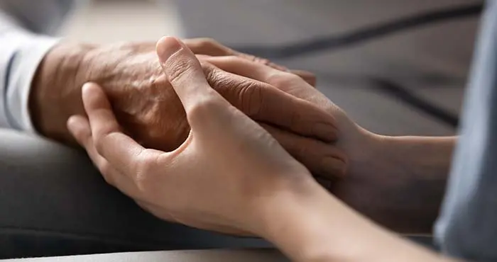 yngre och äldre person håller hand