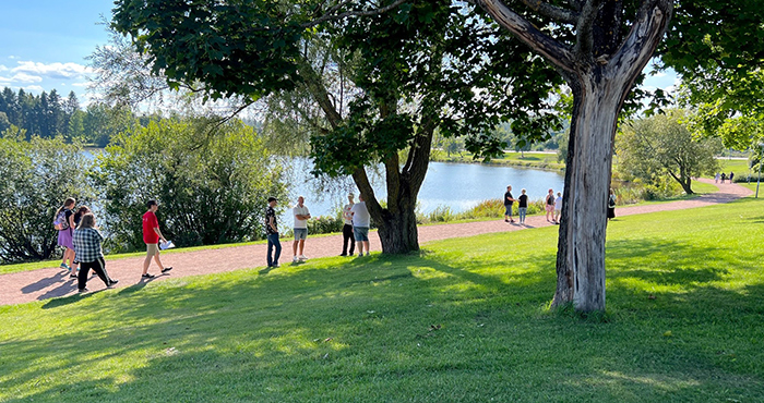 Flera personer som går utmed sjön Vågen i strålande sol.
