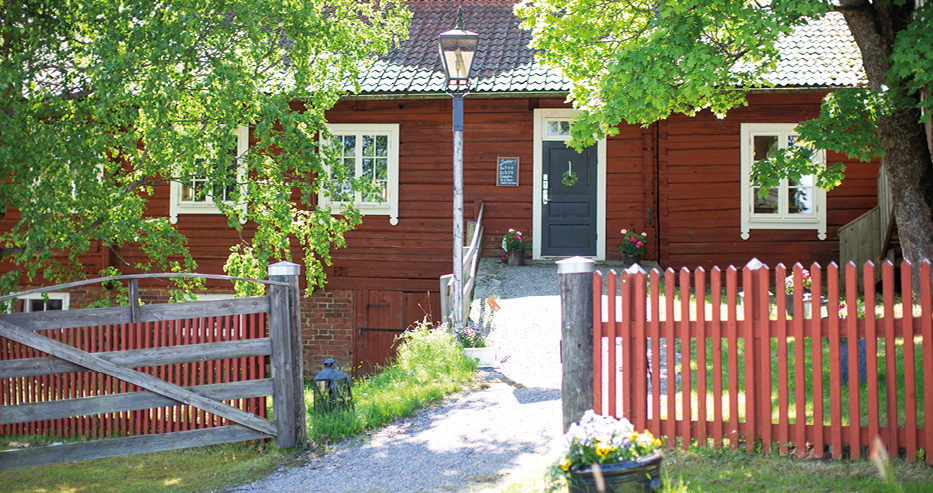 Träslottet i Arbrå sommar med röd byggnad och staket