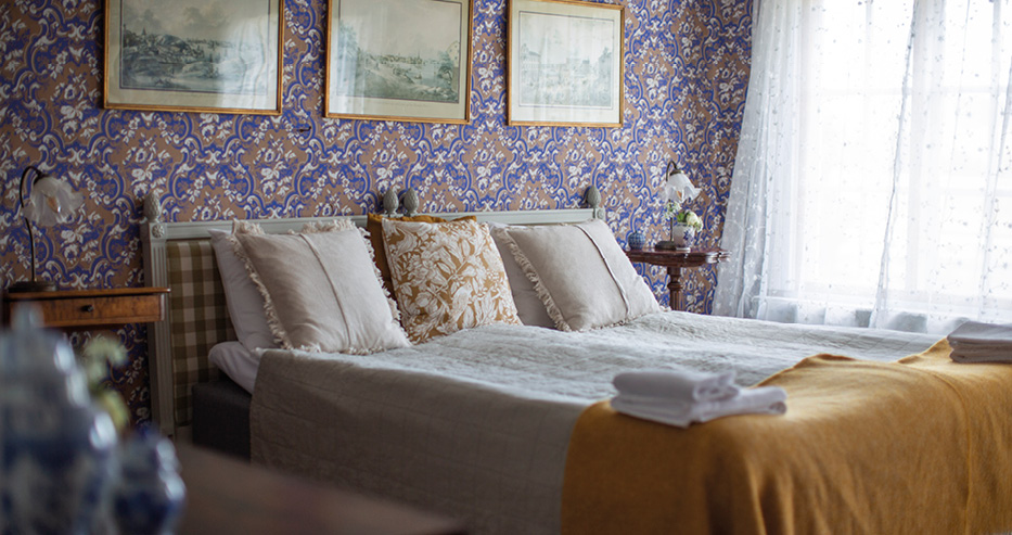 Träslottets Bed & Breakfast rum med blommig blå tapet och dubbelsäng