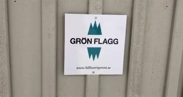 En grön flagg-symbol på en fasad.