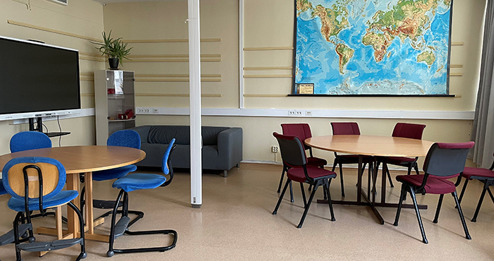 Grupprum med runda bord, stolar, en världskarta och en skärm.