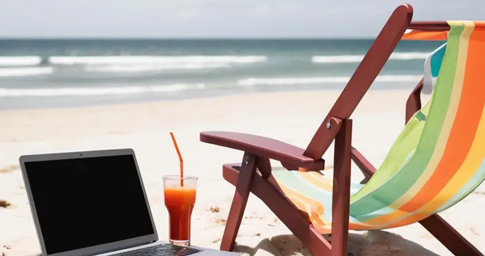 En bärbar dator och solstol på en strand.