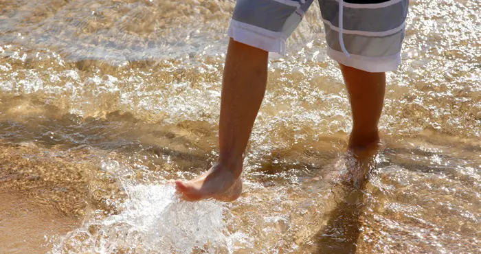 Person som badar fötterna på en sandstrand