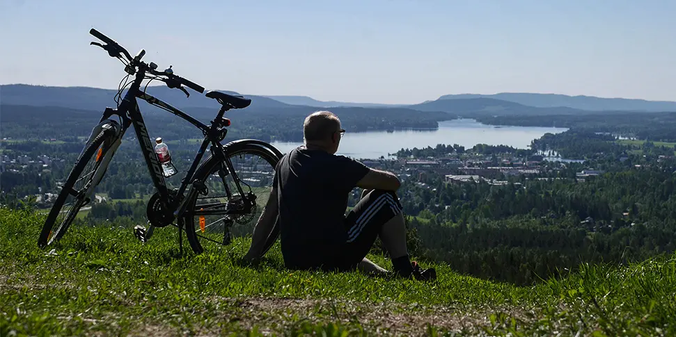 Man sitter vid sidan av en cykel på ett berg