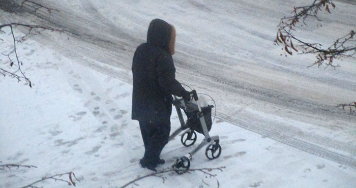 En person med rullator på promenad i snön.