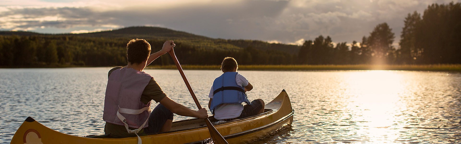 Två personer paddlar kanot på en sjö